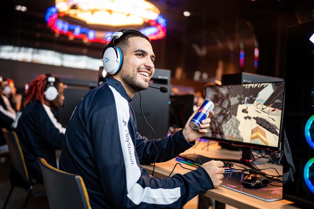 DHM souriant avec un casque micro et une canette de Red Bull, en pleine partie de Minecraft sur scène