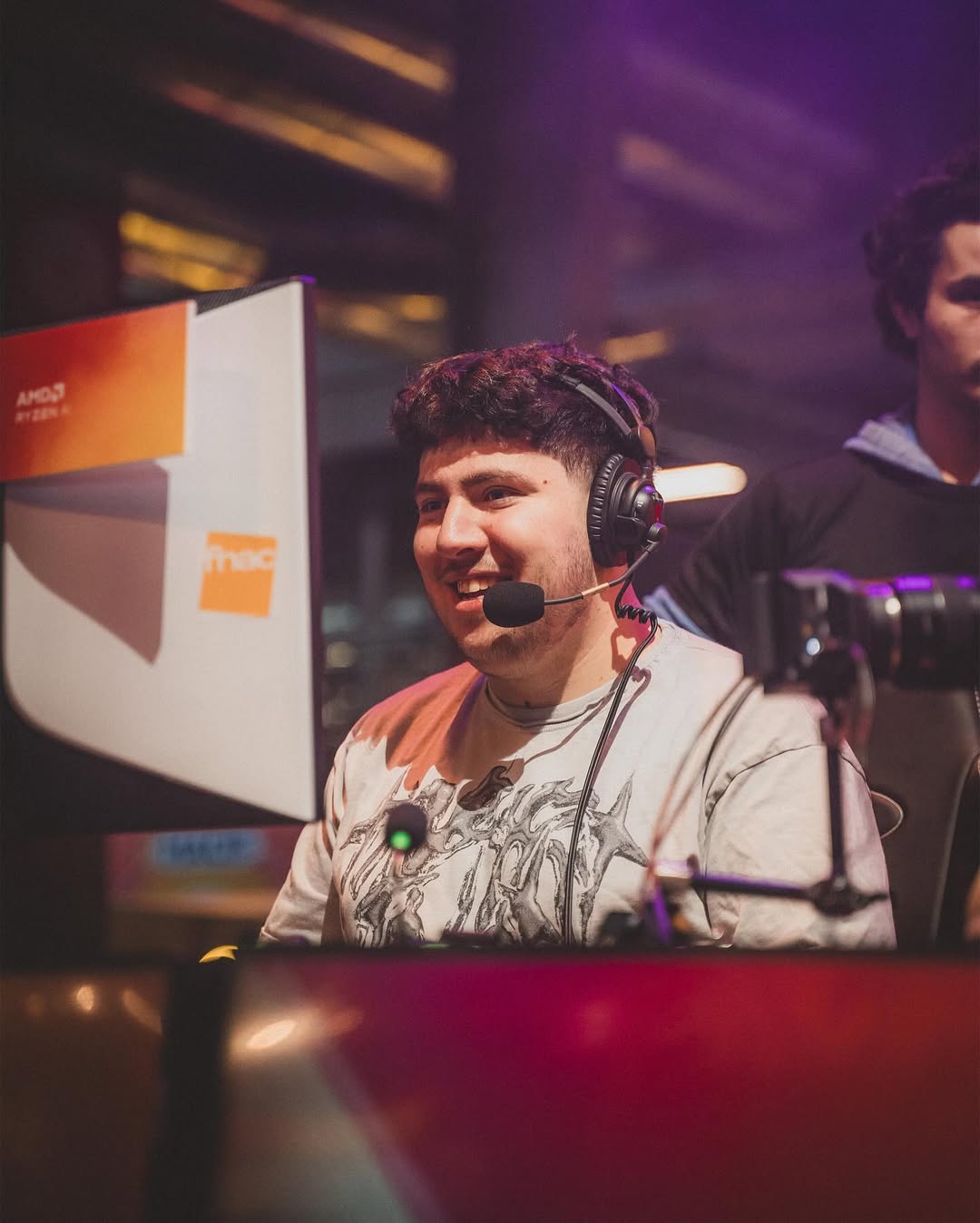 Jinskow souriant avec un casque micro, concentré devant un écran lors d’un show gaming à la Paris Games Week avec Fnac et AMD